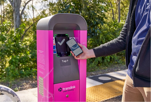 A man purchasing his transit fare by tapping his phone on a platform validator
