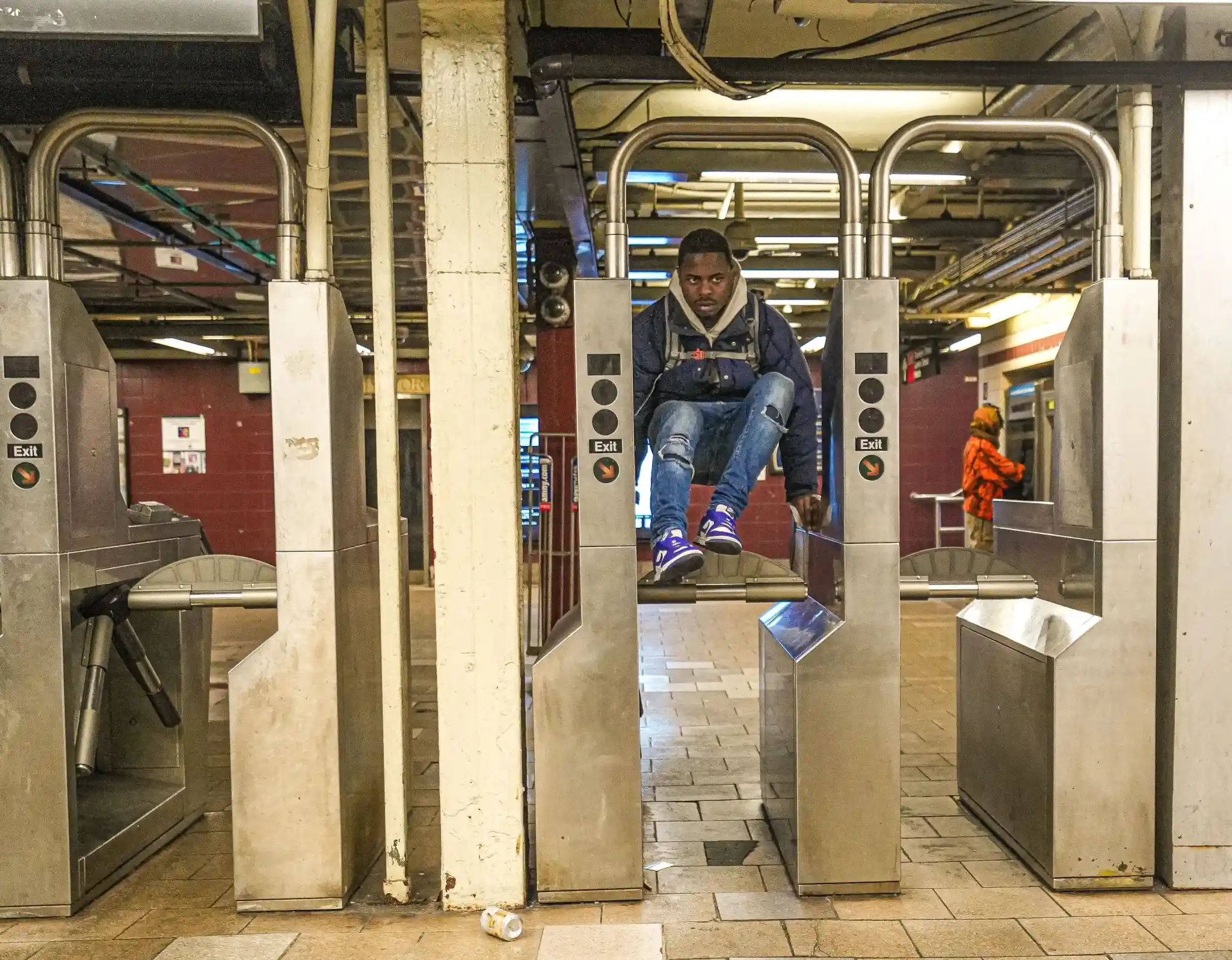 Young man jumping over a fare gate to evade paying his transit fare