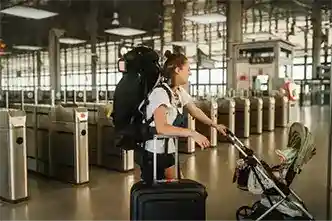 A mom with her baby and luggage getting ready to pass through a fare gate