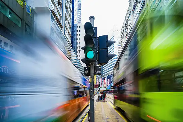 Two buses passing each other at an intersection green light