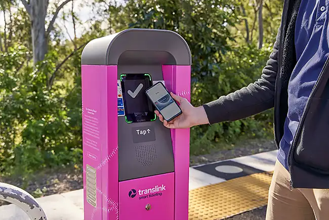 A man purchasing a ticket by tapping his phone on a smart ticketing machine.
